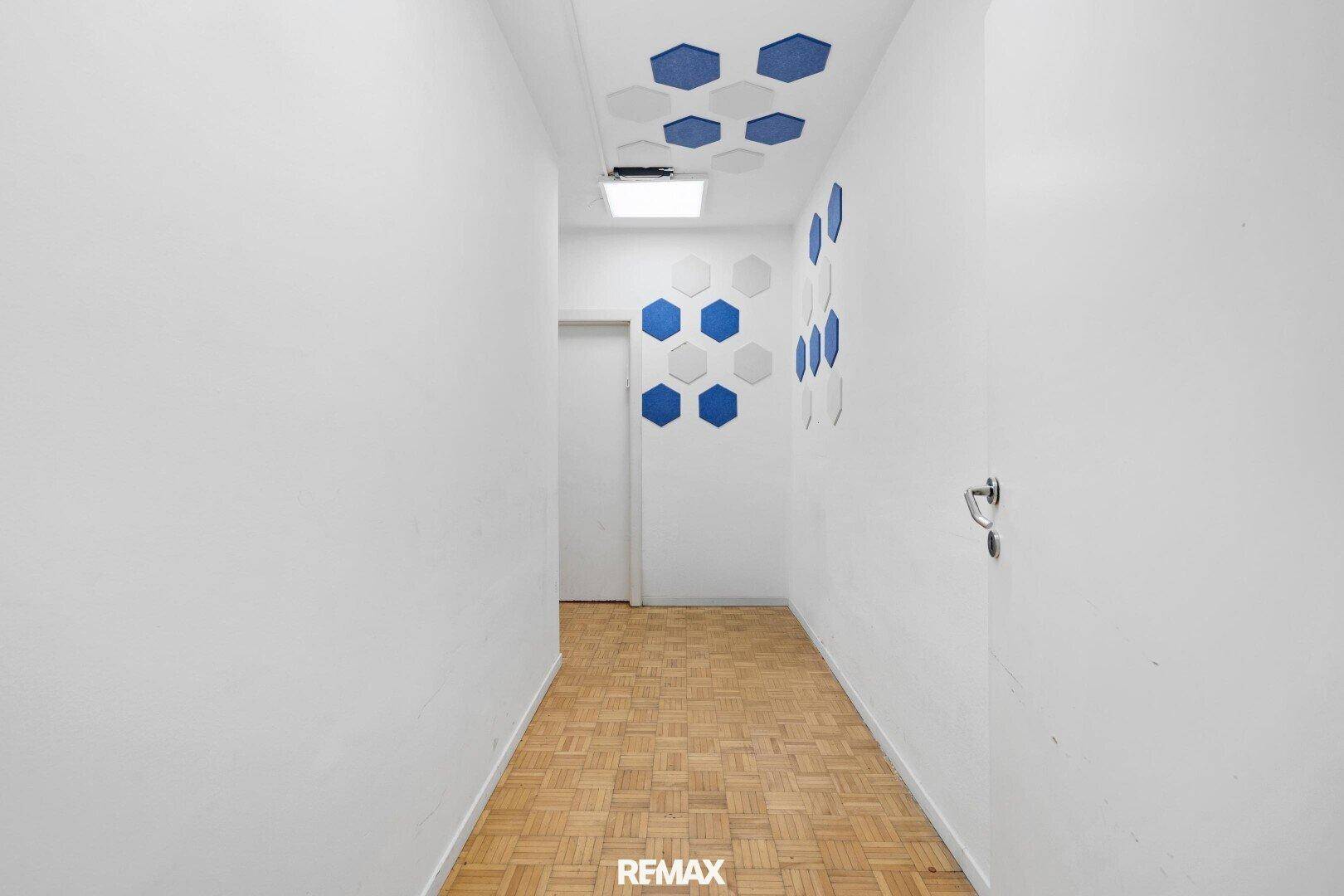 Moderner Flur mit Parkettboden und dekorativen sechseckigen Paneelen an Wand und Decke.