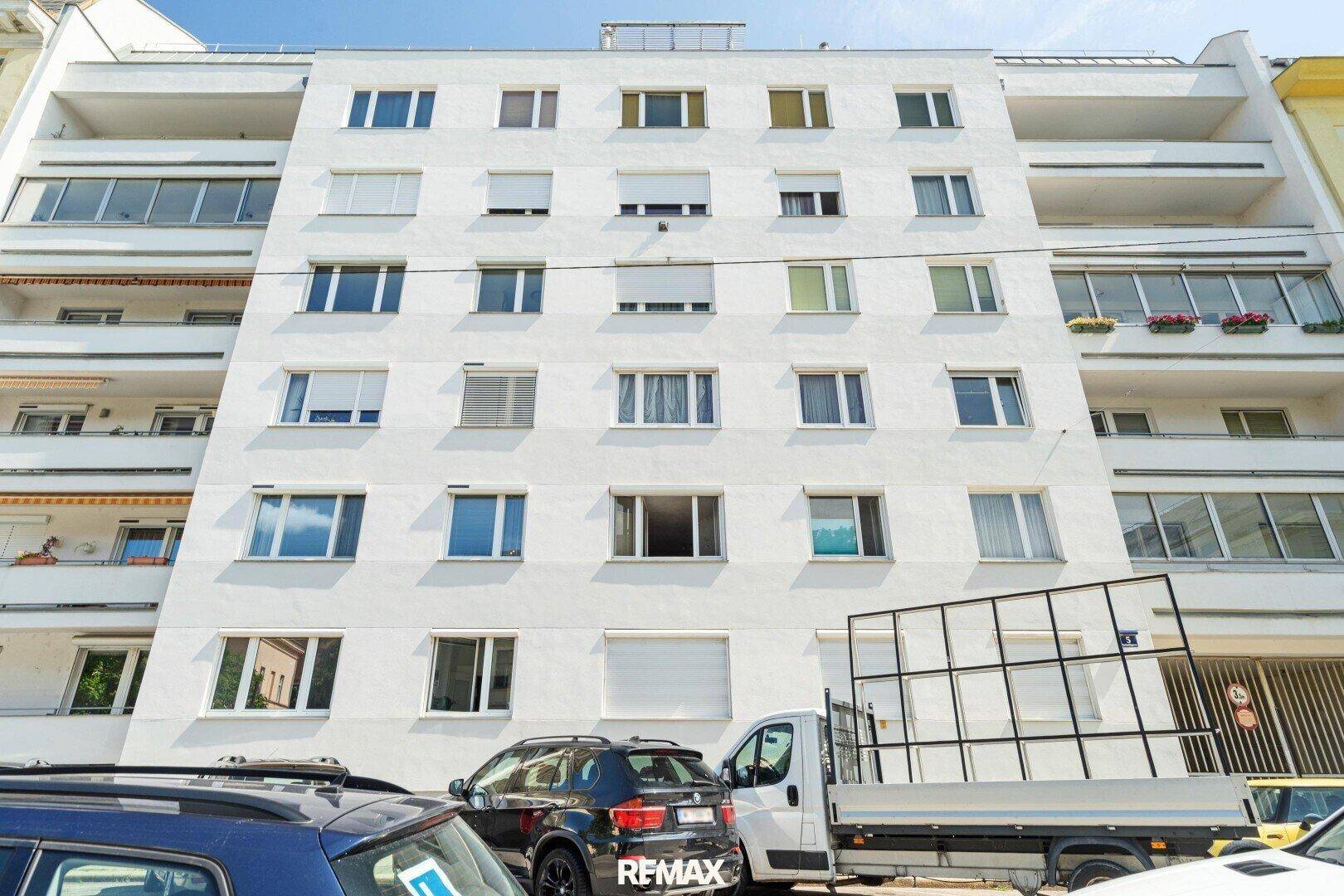 Fassade eines mehrstöckigen Wohngebäudes mit zahlreichen Fenstern und Balkonen.