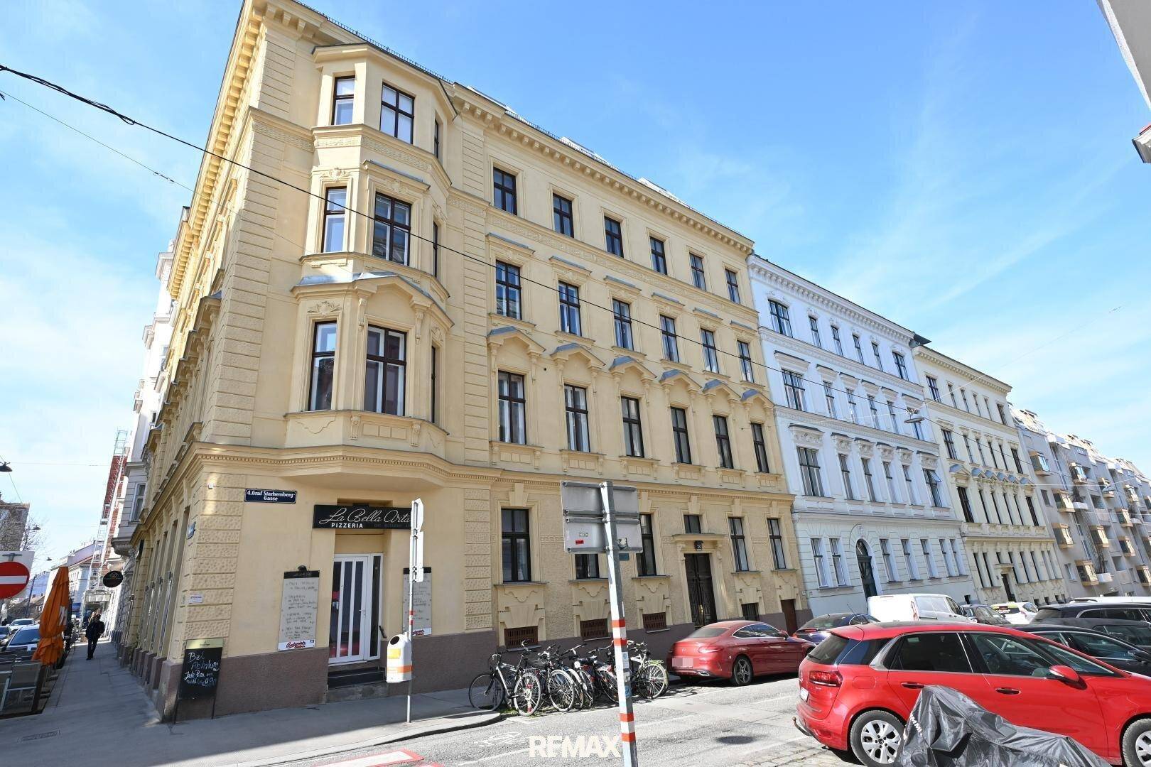 Historisches Gebäude an einer belebten Straße mit klassischer Architektur und vielen Fenstern.