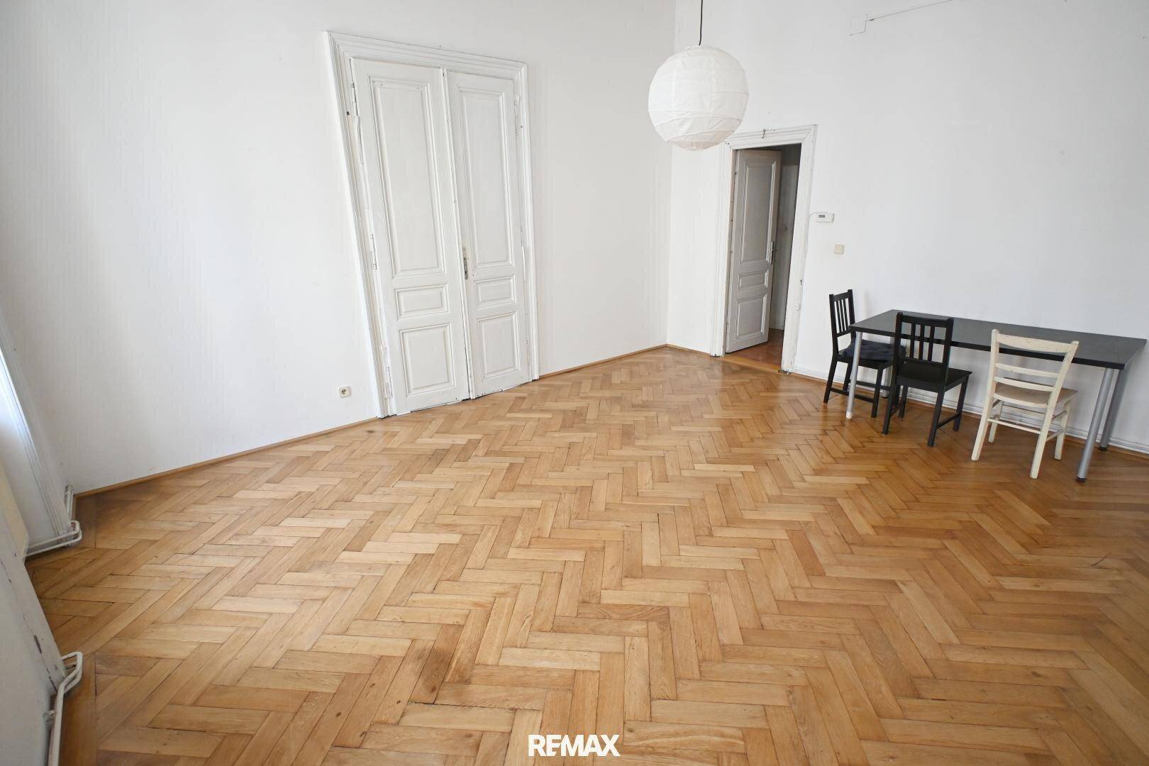 Großes Zimmer mit Fischgrätparkett und klassischen Doppeltüren, bietet vielseitige Nutzungsmöglichkeiten.
