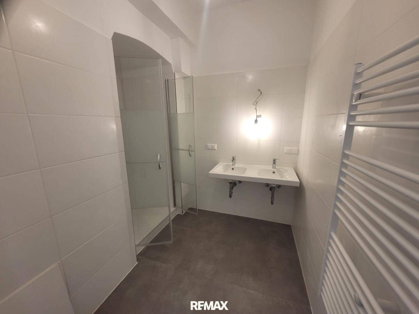 Modernes Badezimmer mit begehbarer Dusche, Doppelwaschbecken und weißen Fliesen.