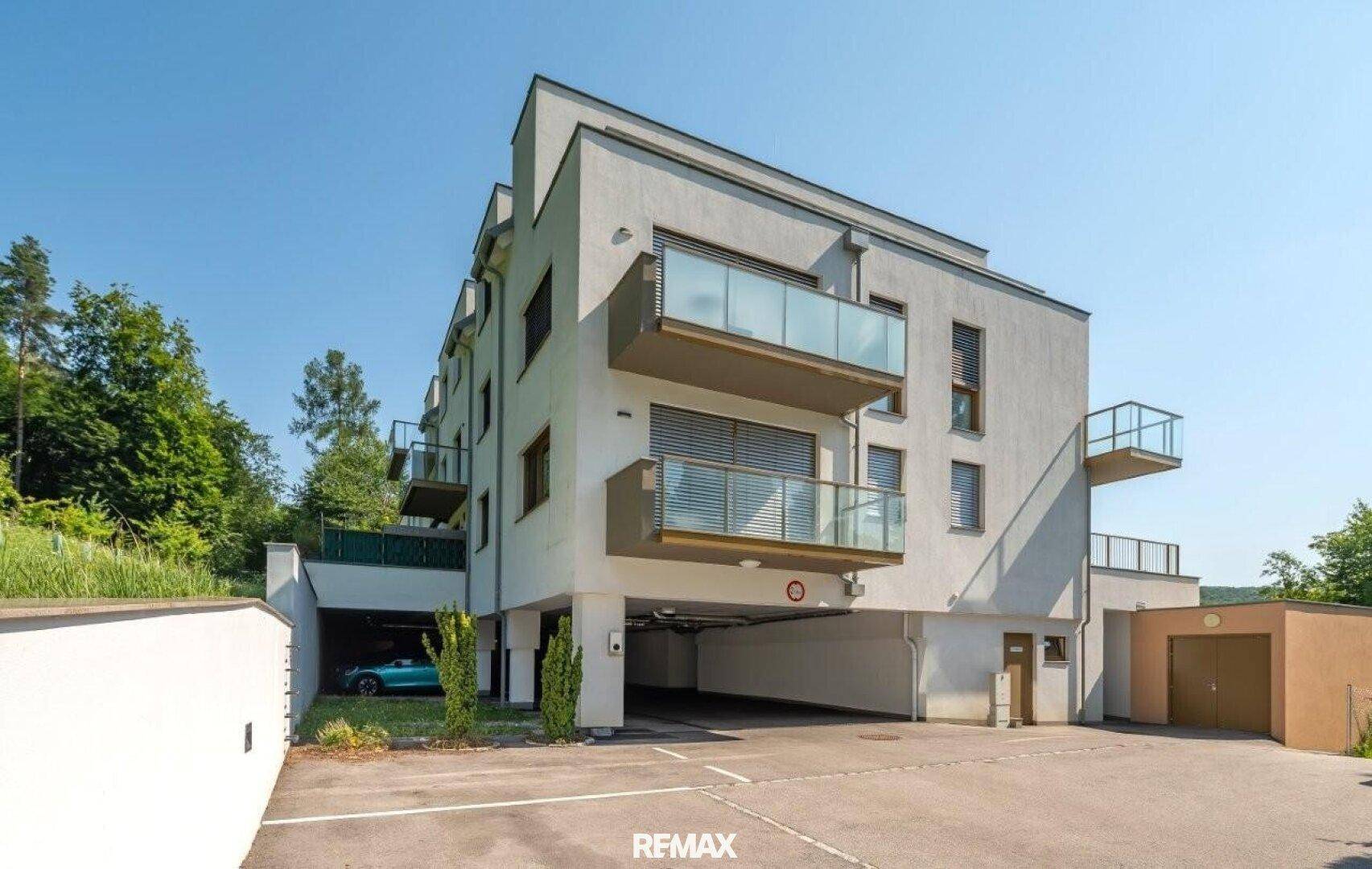 Modernes Mehrfamilienhaus mit Balkonen, Tiefgarage und Außenstellplätzen.