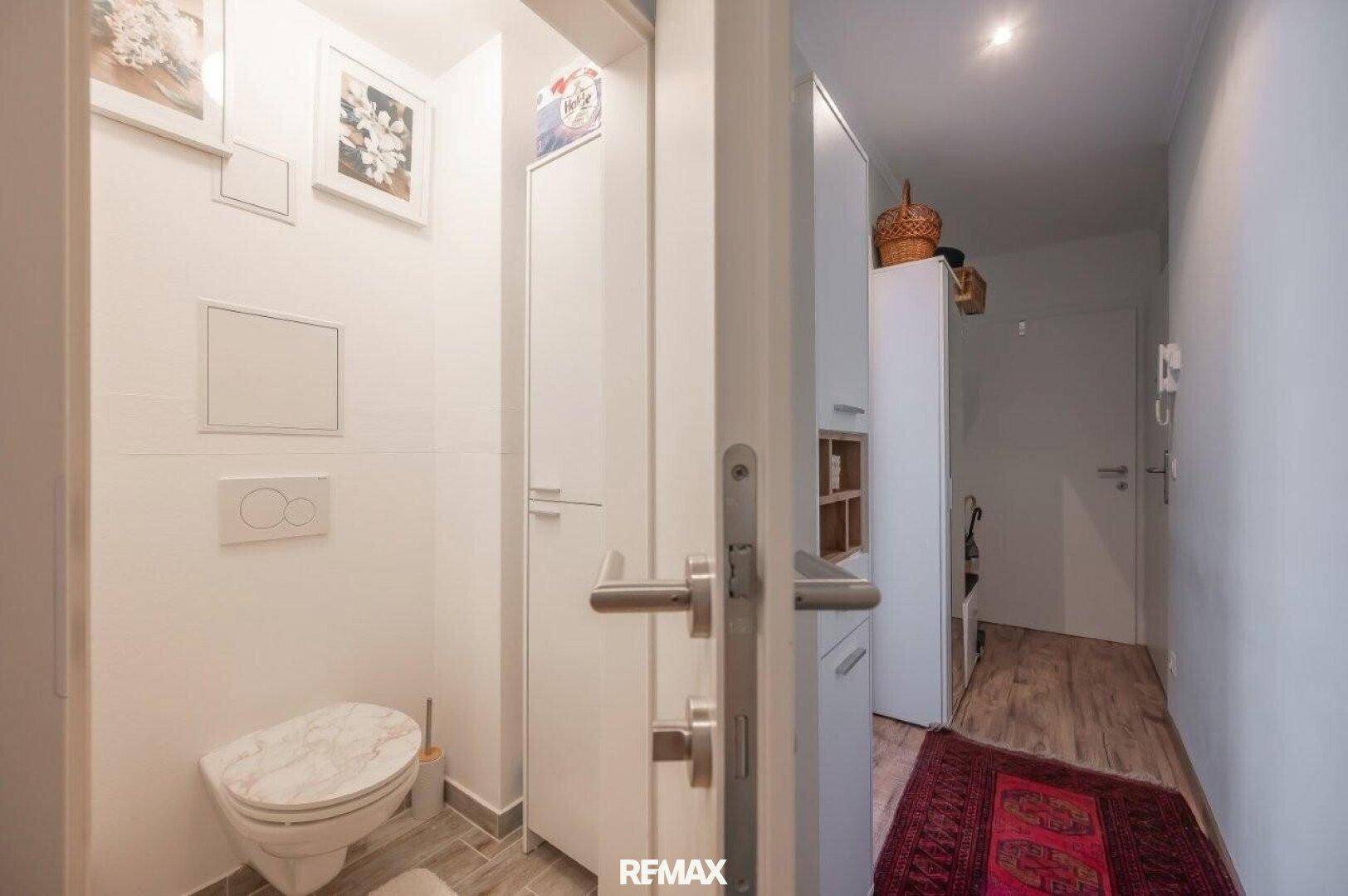 Separates WC mit wandhängender Toilette und Zugang zum Flur.