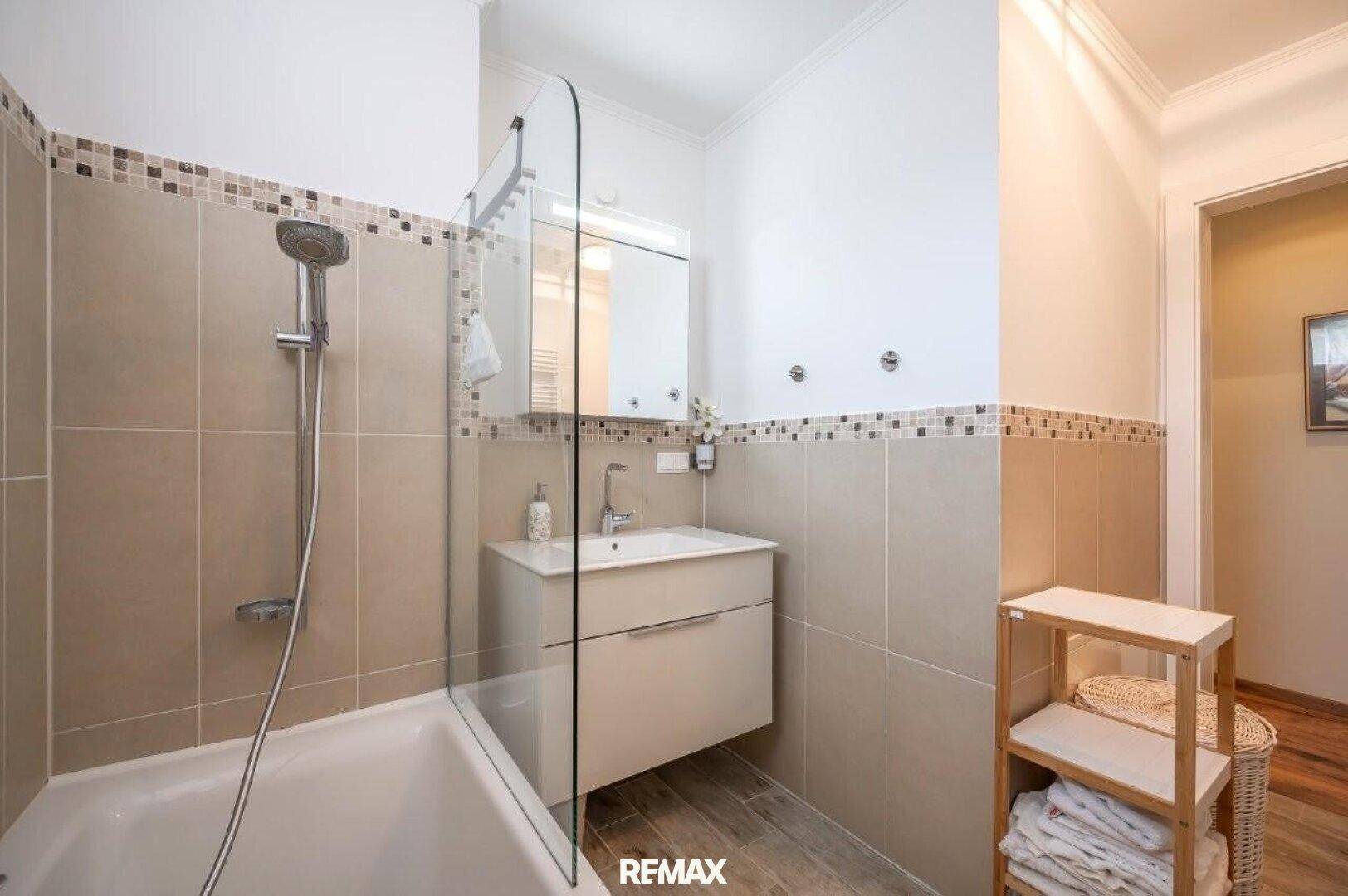 Modernes Badezimmer mit Badewanne, Duschabtrennung und Waschbecken mit Unterschrank.