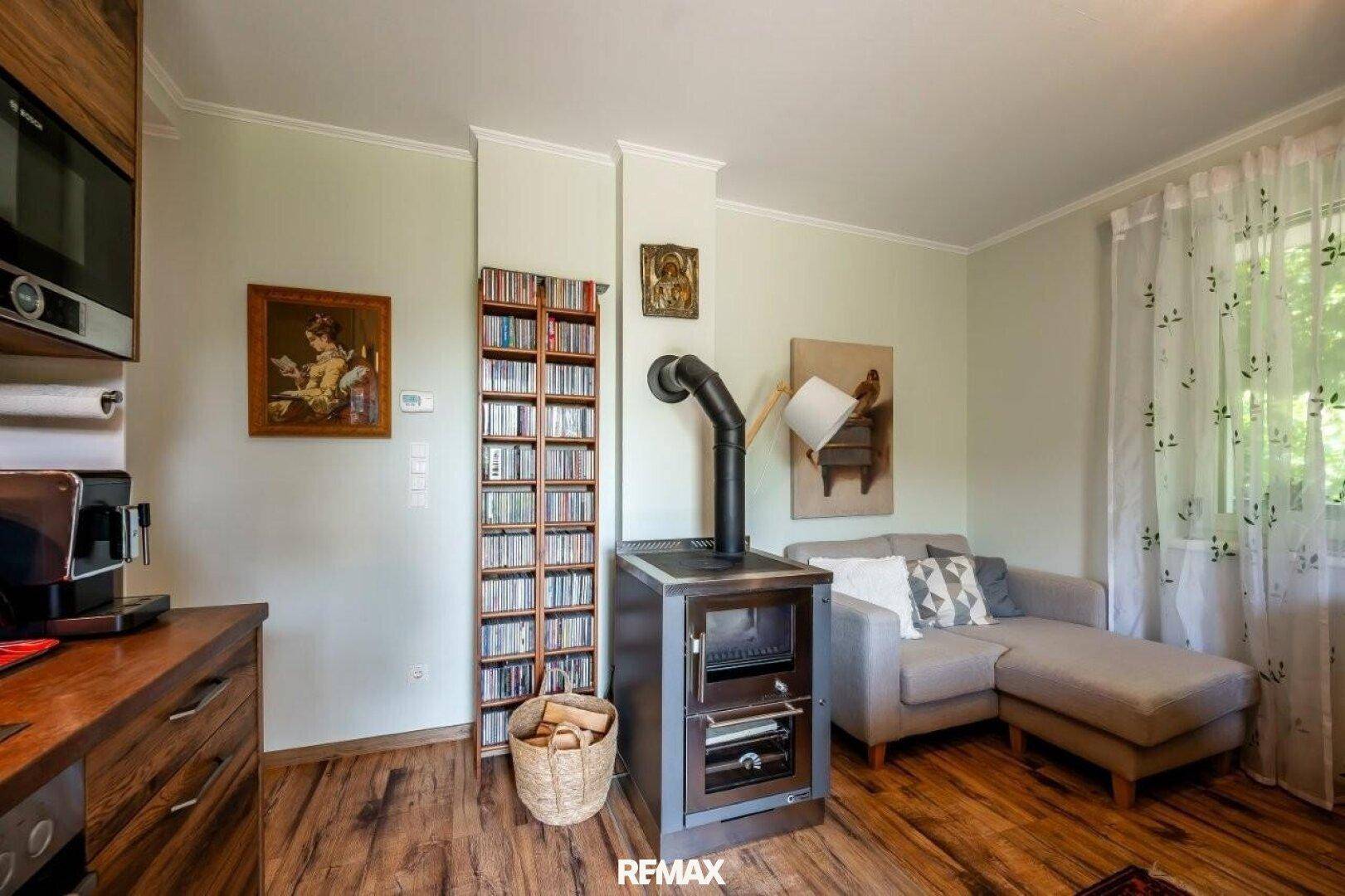 Gemütlicher Wohnbereich mit Holzboden, Sofa und einem modernen Holzofen.