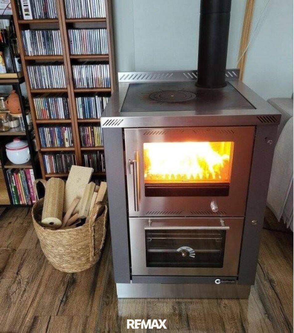 Detailaufnahme eines modernen Holzofens mit brennendem Feuer und Holzscheiten.