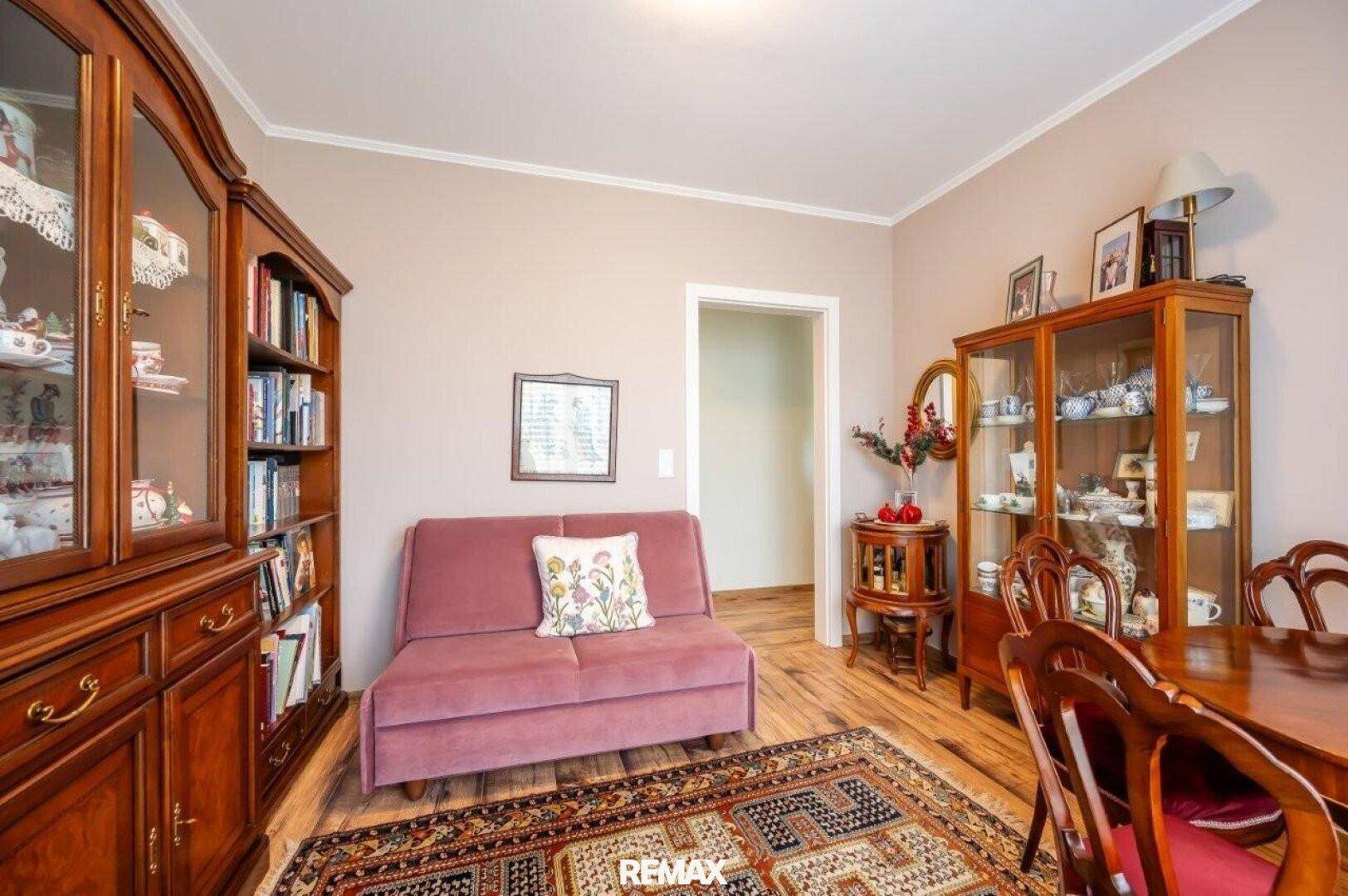 Gemütlicher Essbereich mit traditionellen Holzmöbeln, Teppich und einem Sofa.