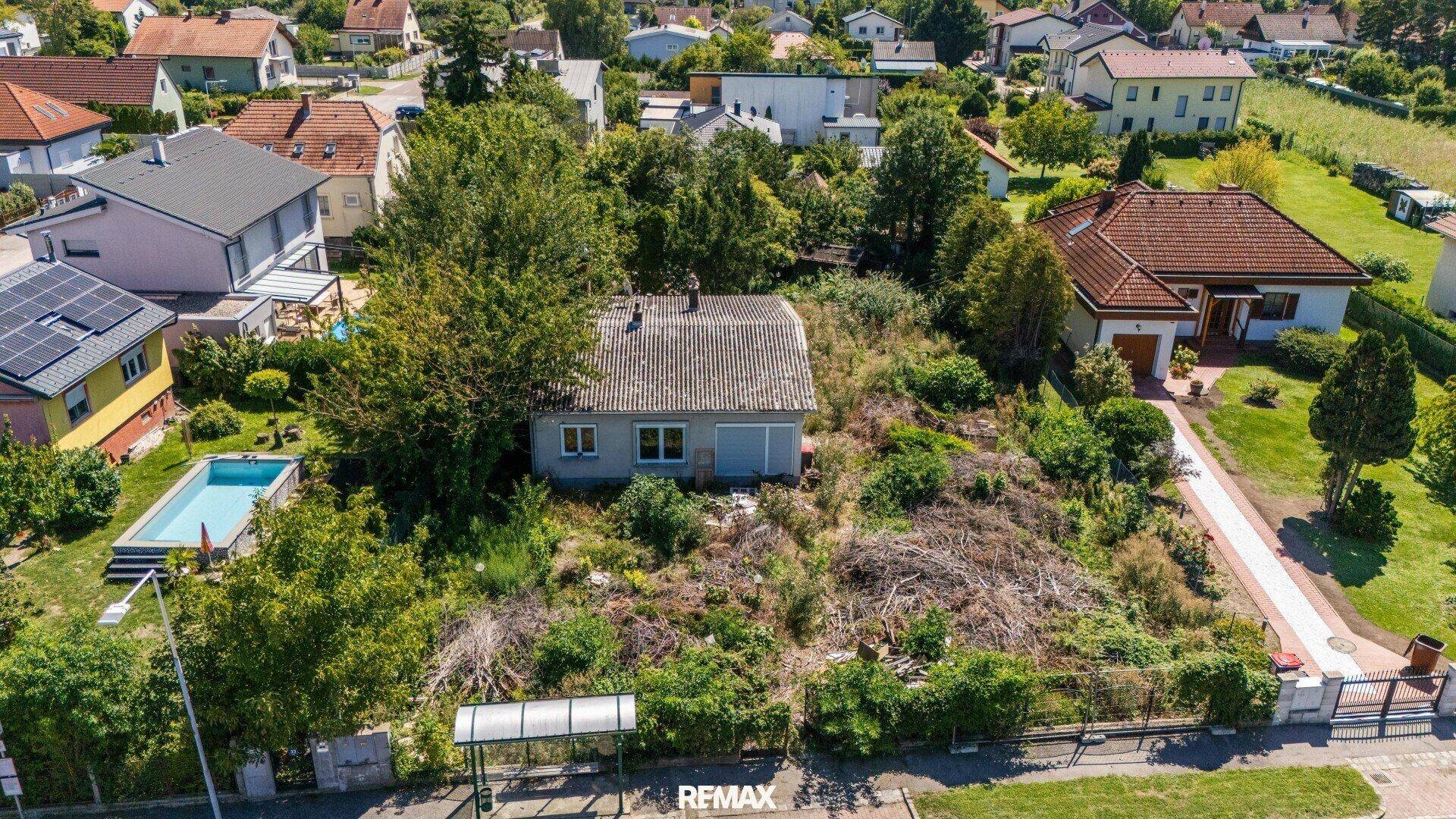 Luftaufnahme des Grundstücks mit dem Bestandsgebäude und einem Nachbarhaus mit Pool.