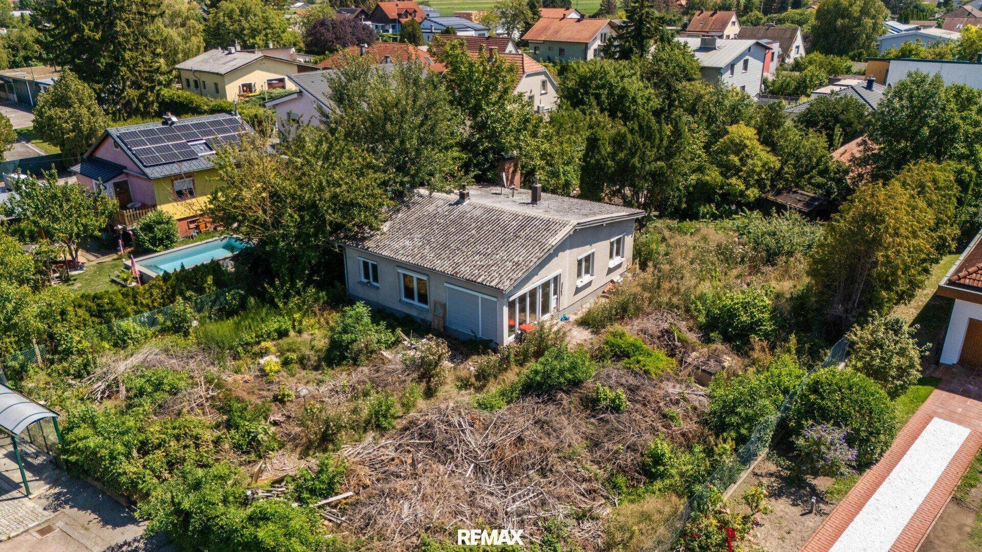 Luftaufnahme des Grundstücks mit dem Haus, umgeben von Bäumen und einer Straße im Vordergrund.