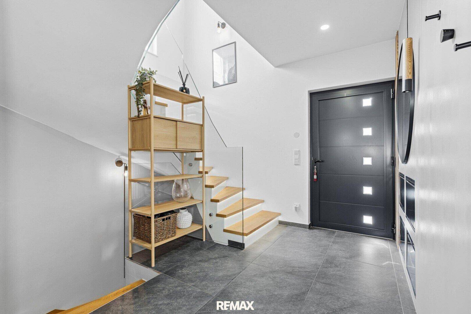 Heller Eingangsbereich mit moderner Haustür, Treppe und Fliesenboden.