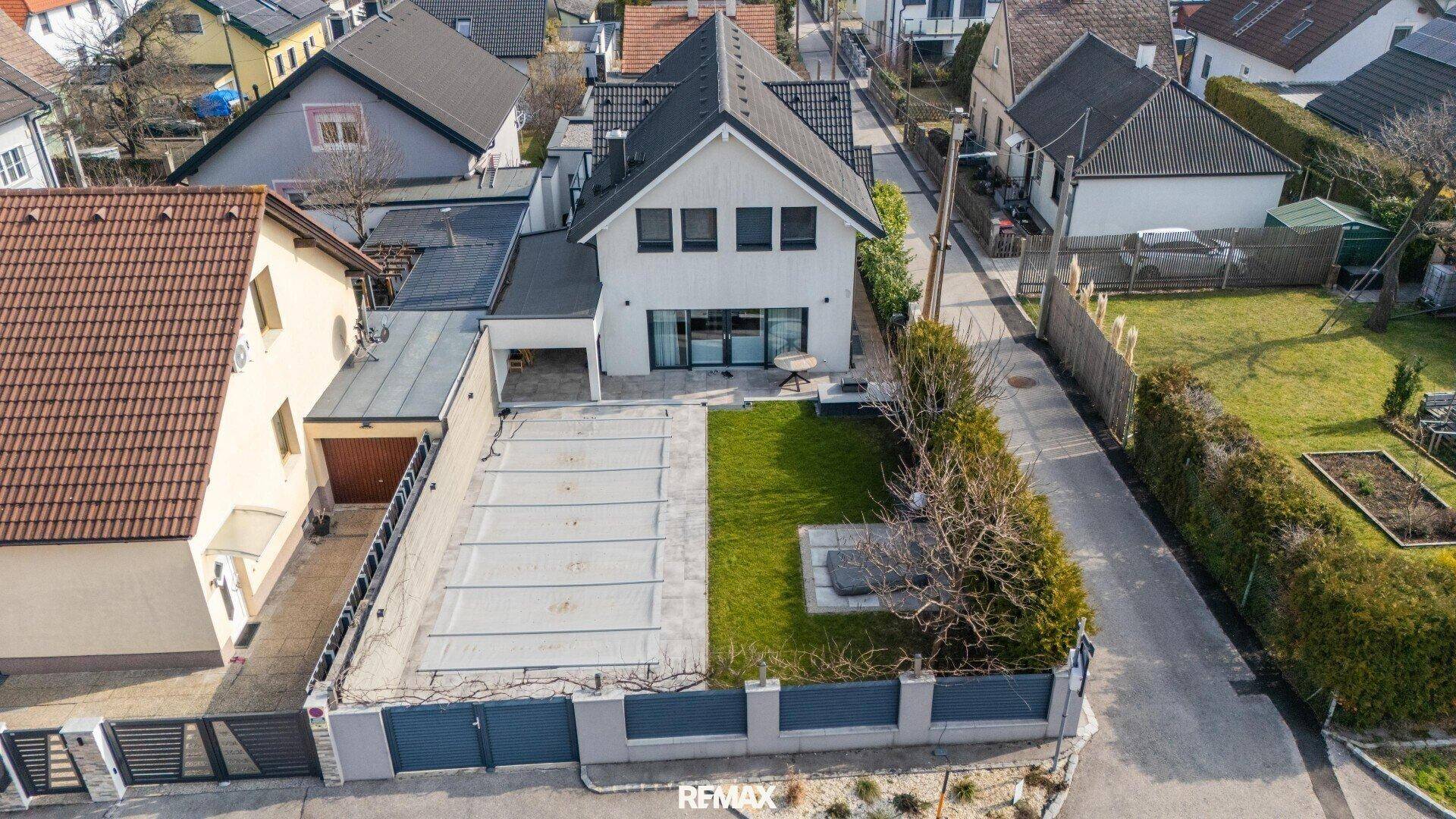 Luftaufnahme des Hauses mit Garten, Rasenfläche und abgedecktem Poolbereich.