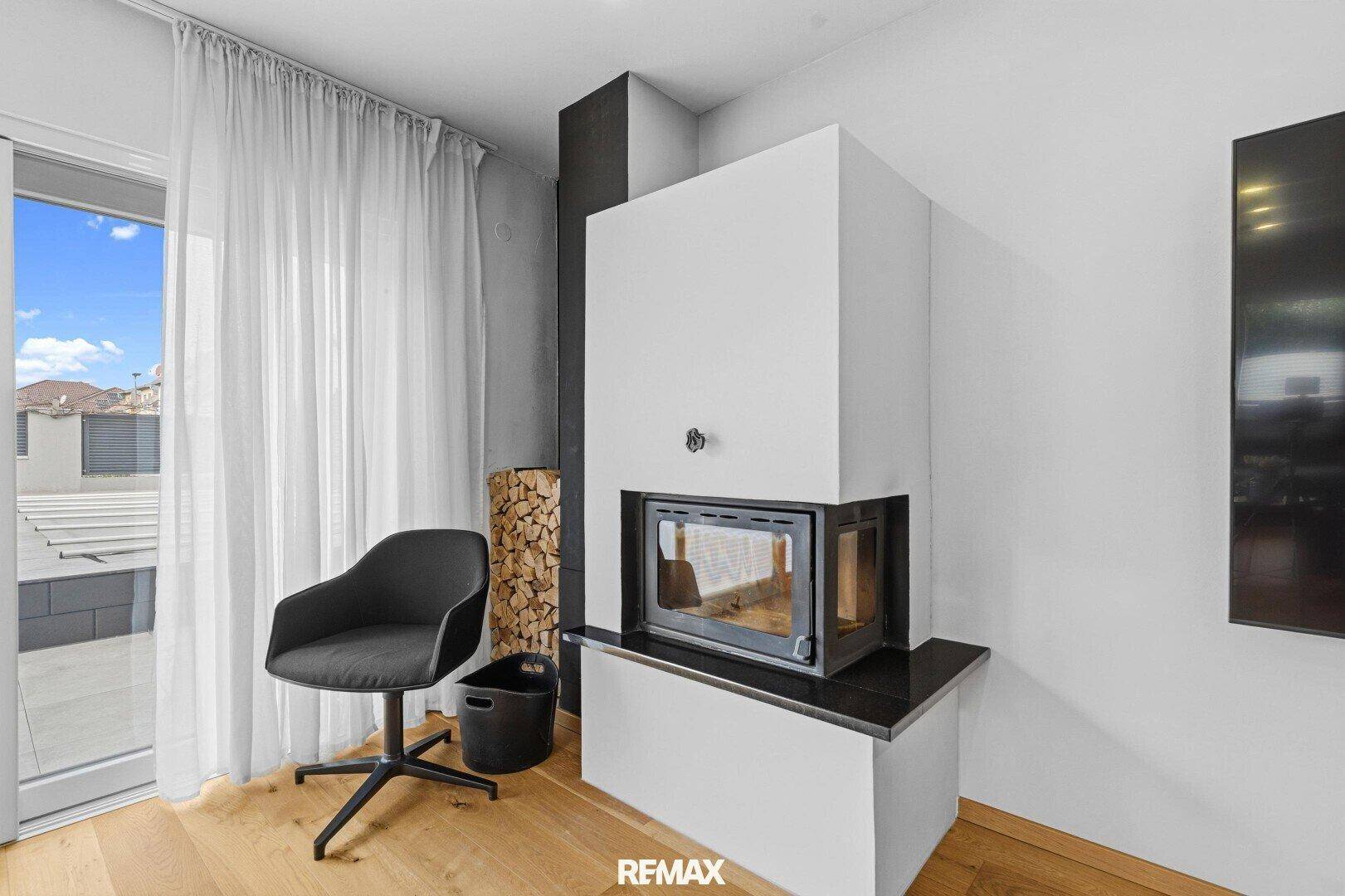 Moderner Kamin im Wohnzimmer mit Holzscheiten und stilvollem Sessel.
