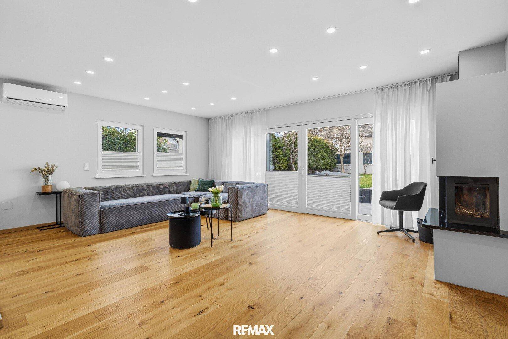 Geräumiges Wohnzimmer mit großem Sofa, Kamin und Zugang zur Terrasse.