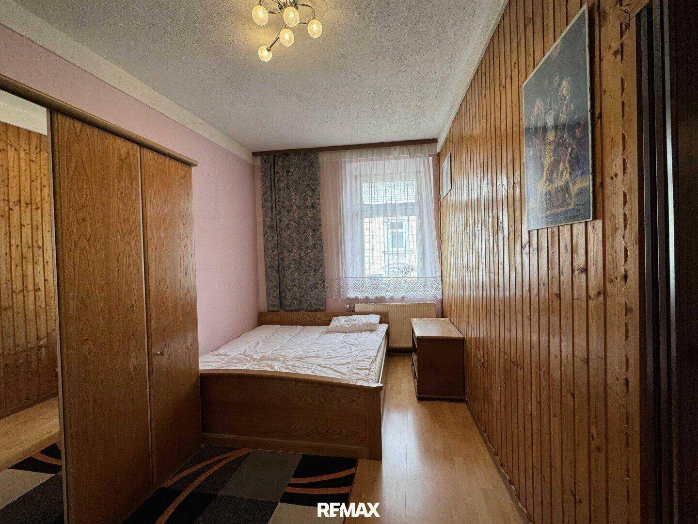 Schlafzimmer mit Holzvertäfelung, Einzelbett und großem Kleiderschrank.