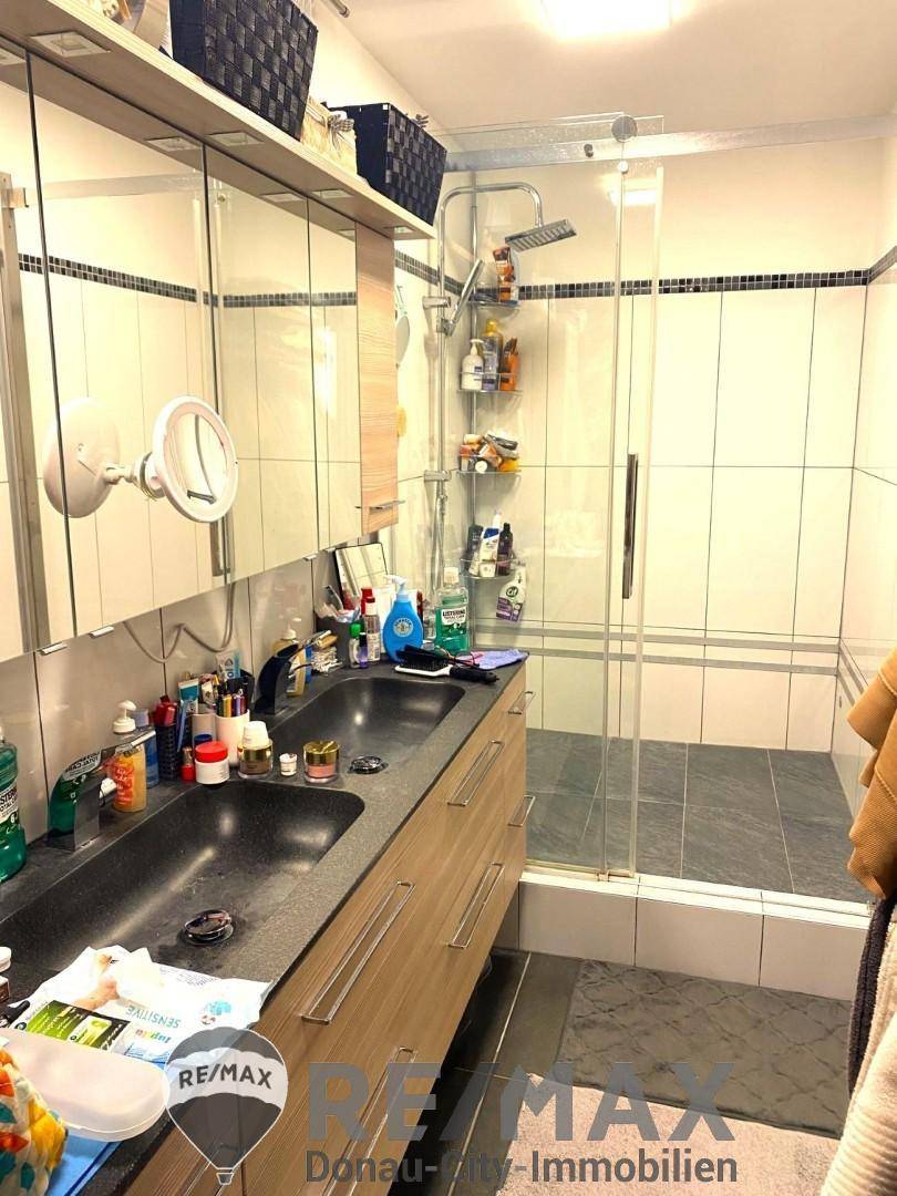 Modernes Badezimmer mit Doppelwaschbecken, Spiegelschrank und großer Duschkabine.
