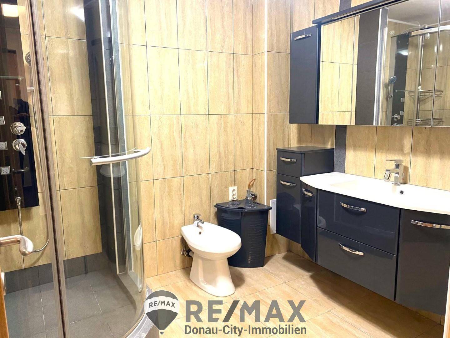 Modernes Badezimmer mit Duschkabine, Bidet und Waschtisch mit dunklen Unterschränken.