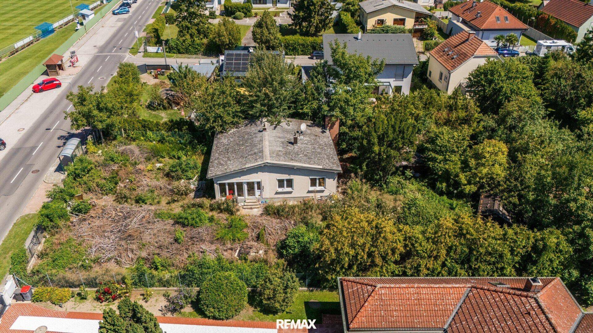 Luftaufnahme des Hauses mit großem Grundstück, umgeben von Bäumen und einer deutlichen Grundstücksgrenze.