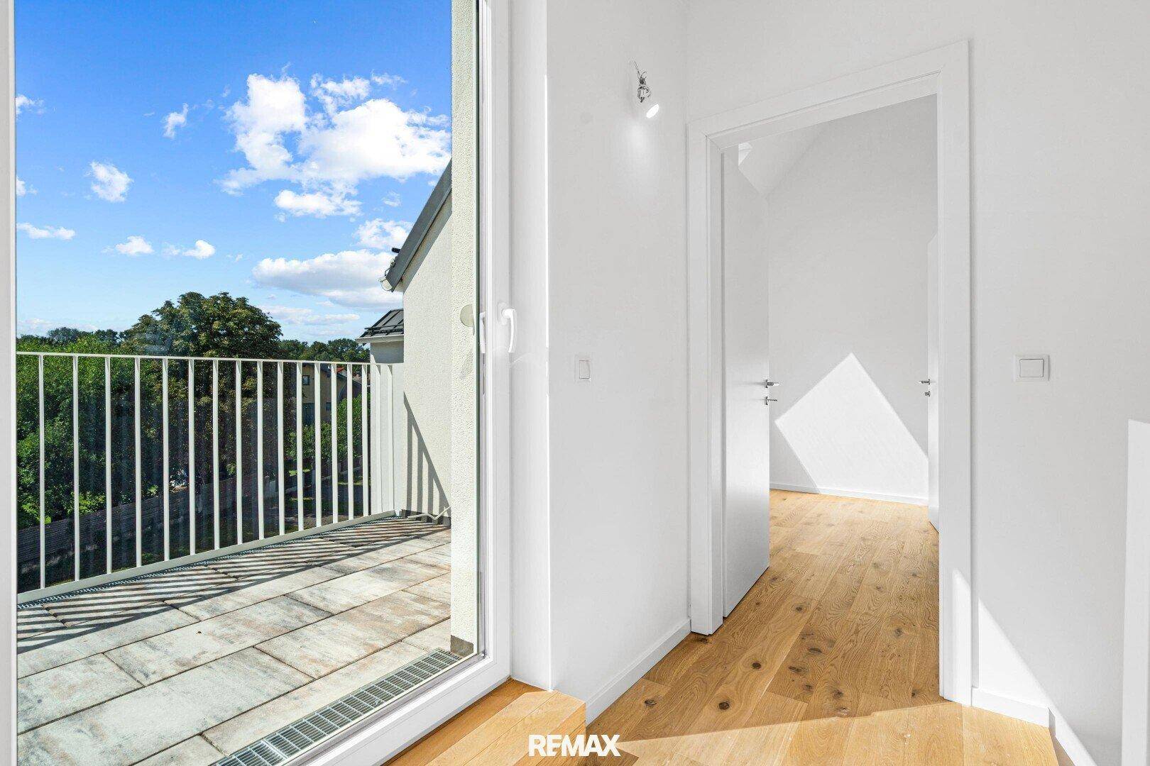 Heller Flur mit Zugang zu einem Balkon, der einen weiten Blick bietet.