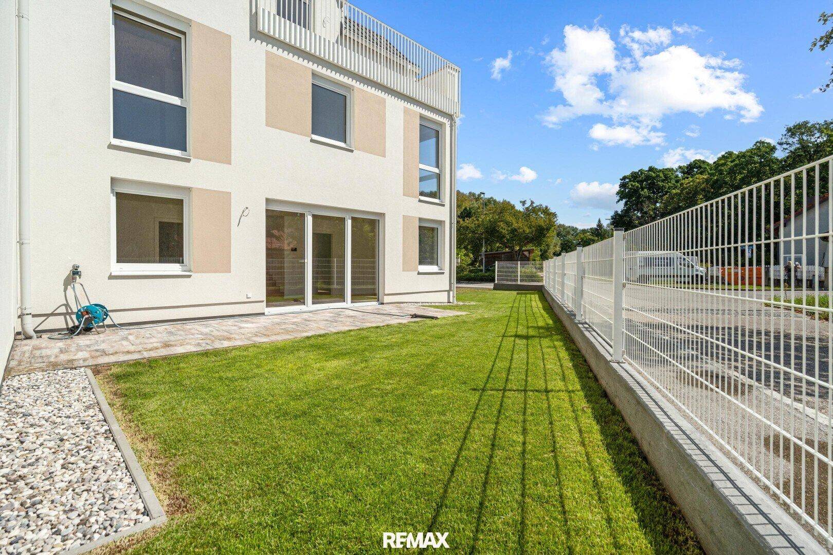 Gepflegter Gartenbereich mit kleiner Terrasse und Rasenfläche neben dem Neubau.