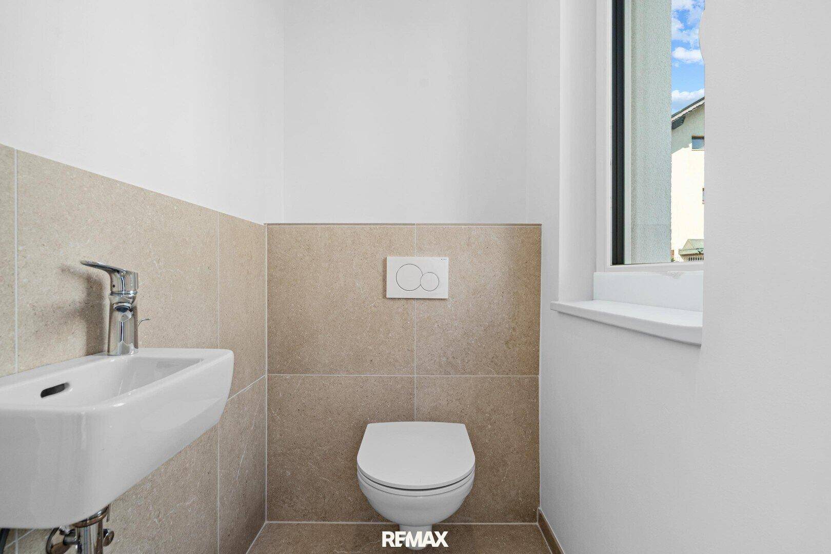 Modernes Gäste-WC mit Wand-WC, kleinem Waschbecken und beigefarbenen Fliesen.