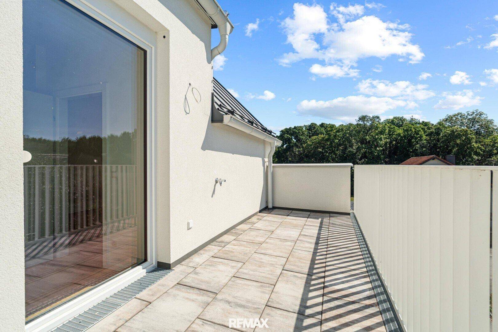 Geräumiger Balkon mit Fliesenboden und Metallgeländer, ideal für Entspannung im Freien.