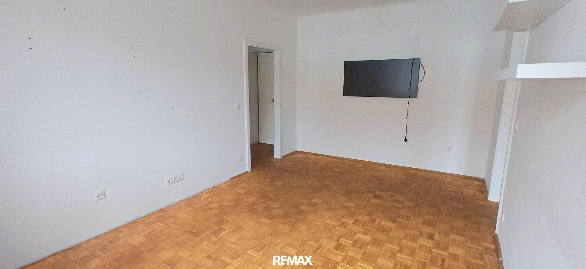 Geräumiges Zimmer mit Parkettboden und vorbereiteter Wandmontage für einen Fernseher.