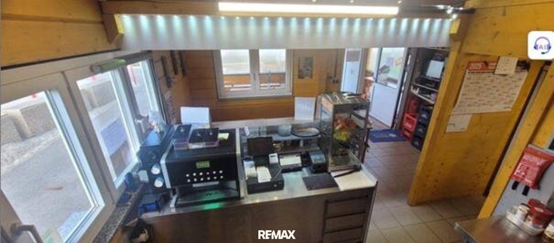 Thekenbereich eines Imbisses mit Kaffeemaschine, Kassensystem und Blick auf den Essbereich.