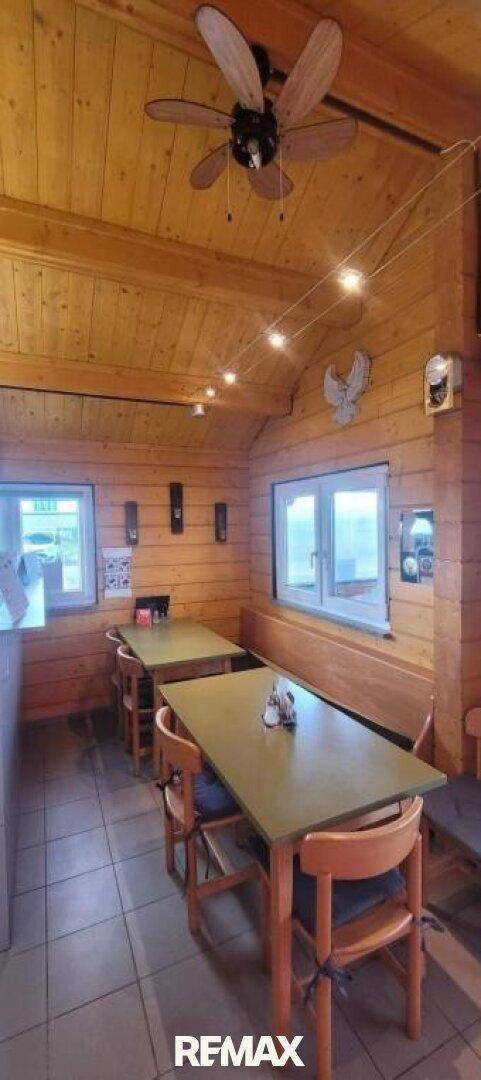 Essbereich mit Holzwänden, Deckenventilator und mehreren Tischen für Gäste.
