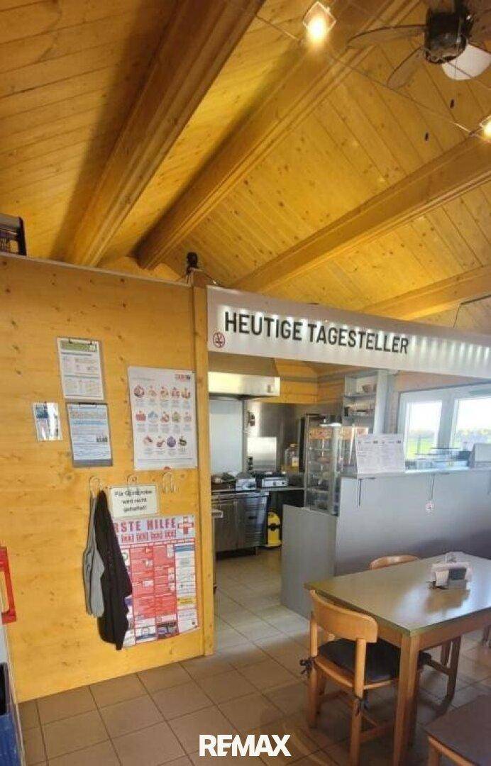 Übergangsbereich von der Theke zum Essbereich mit Holzwänden und Informationsaushängen.