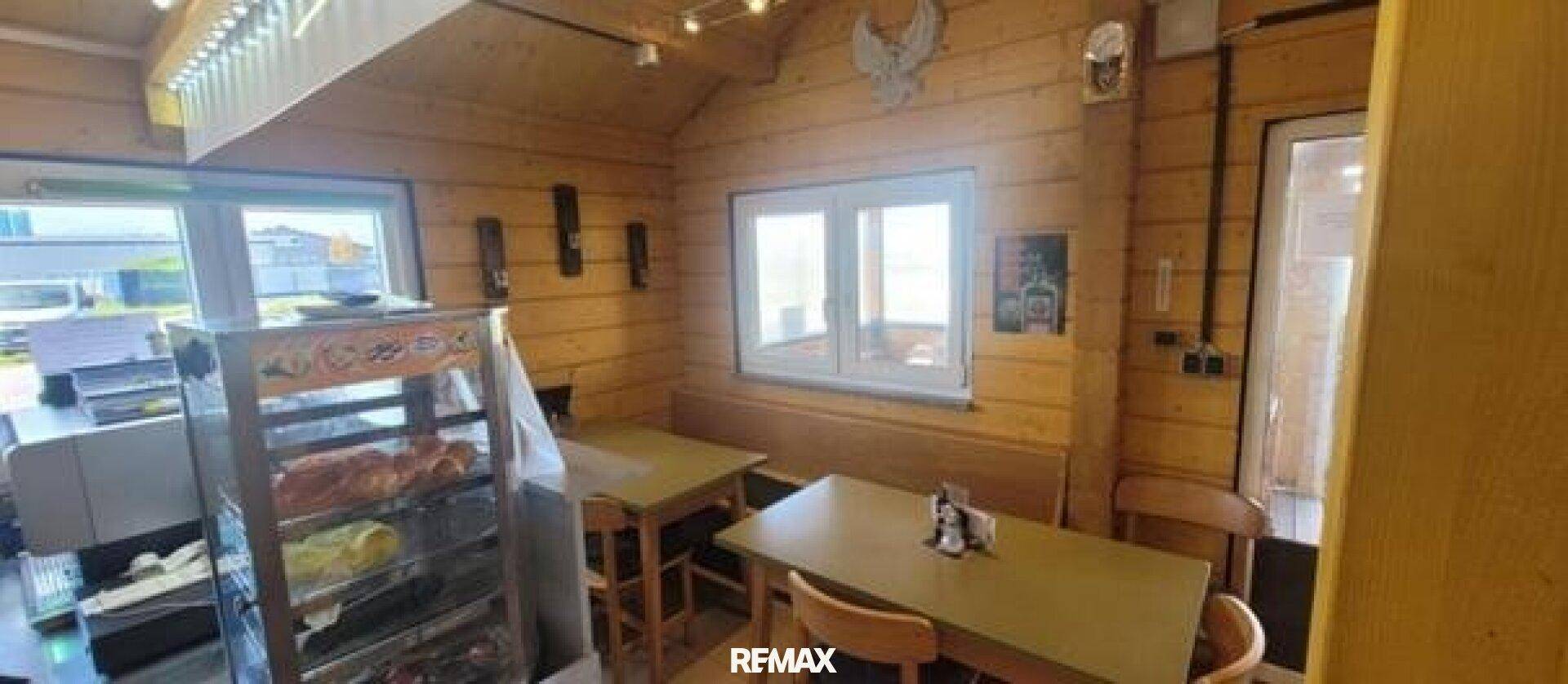 Gemütlicher Essbereich mit Holztischen, Bänken und Fenstern in einem Imbisslokal.