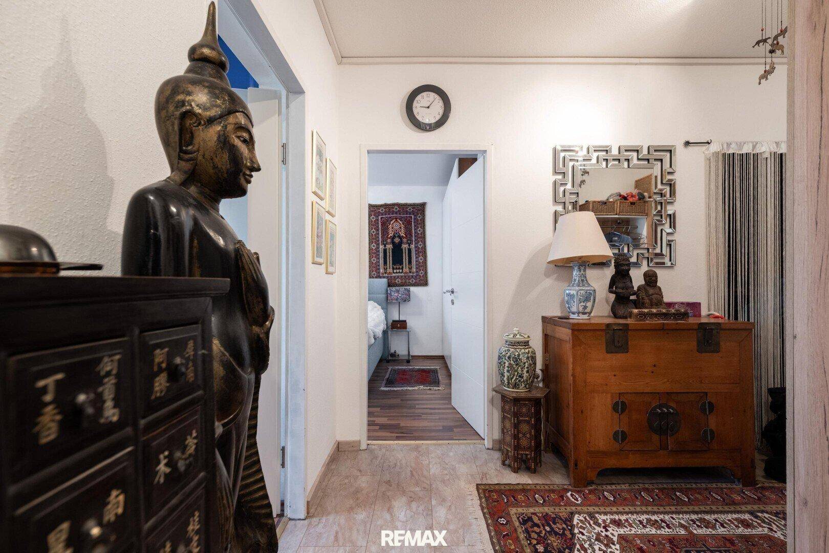Heller Flur mit dekorativen Elementen und Blick in ein Schlafzimmer.