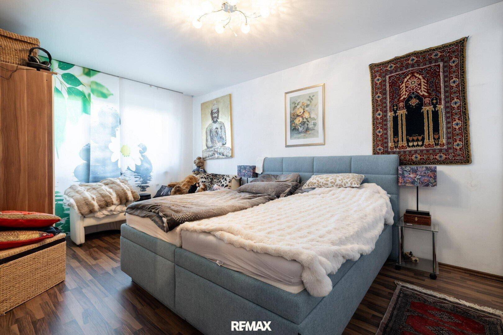 Schlafzimmer mit Doppelbett, Holzboden und orientalischen Teppichen an der Wand.