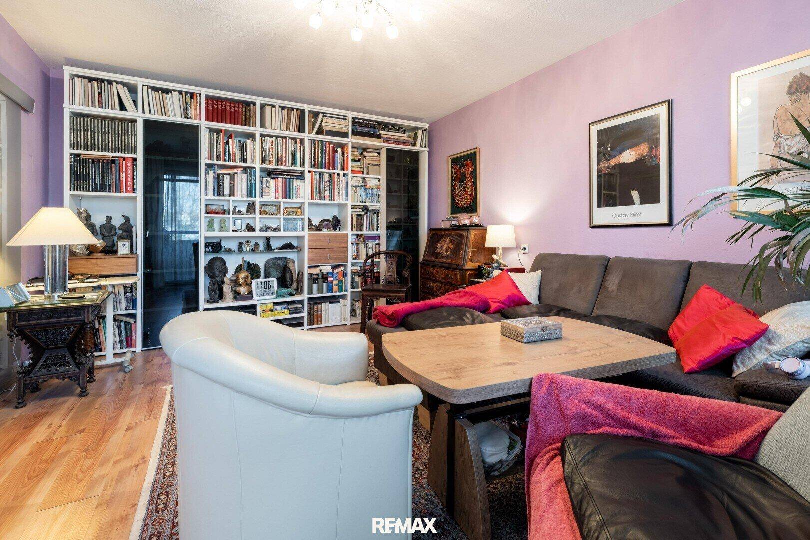 Wohnzimmer mit großer Bücherwand, Sofa und Holzboden.