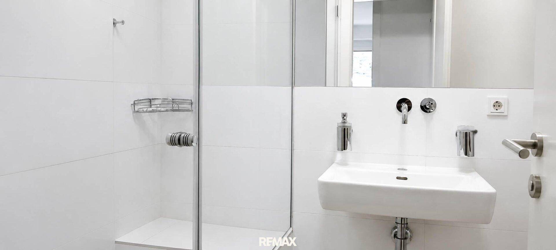 Modernes Badezimmer mit begehbarer Dusche, wandmontiertem Waschbecken und Spiegel.