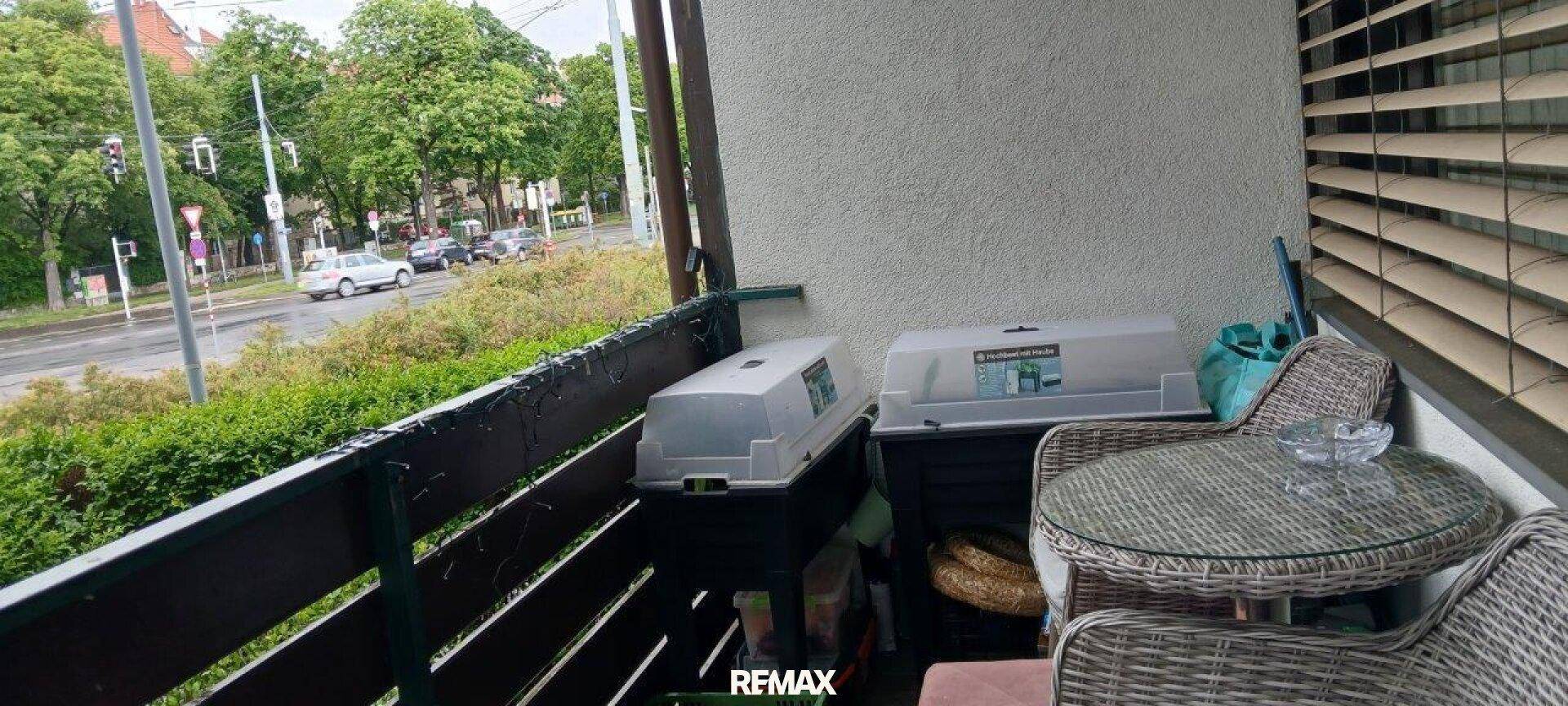 Balkon mit Sitzgelegenheiten und Blick auf die Straße und umliegende Bäume.