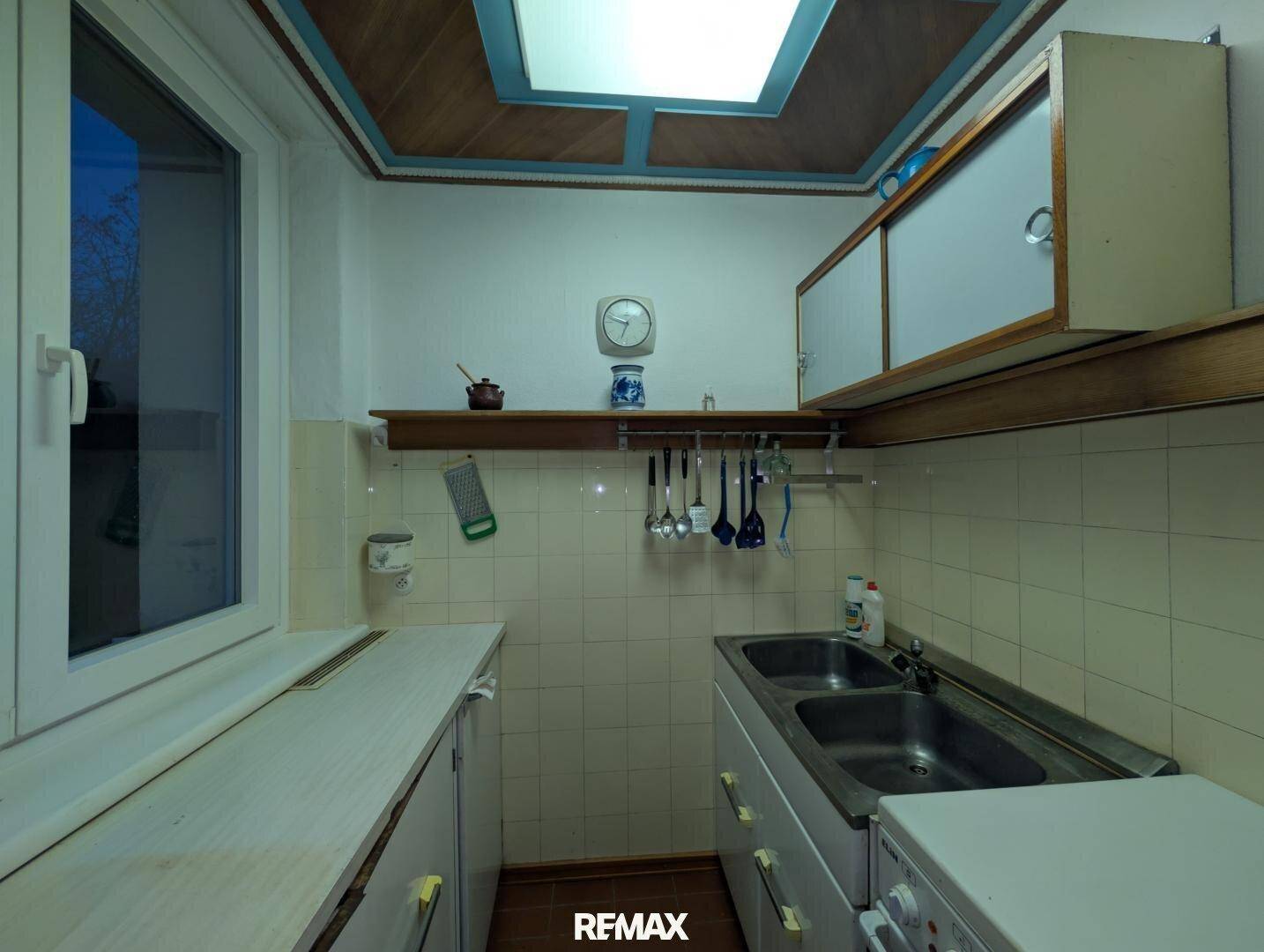 Kleine Küche mit funktionaler Ausstattung, Fliesenrückwand und Fenster für Tageslicht.