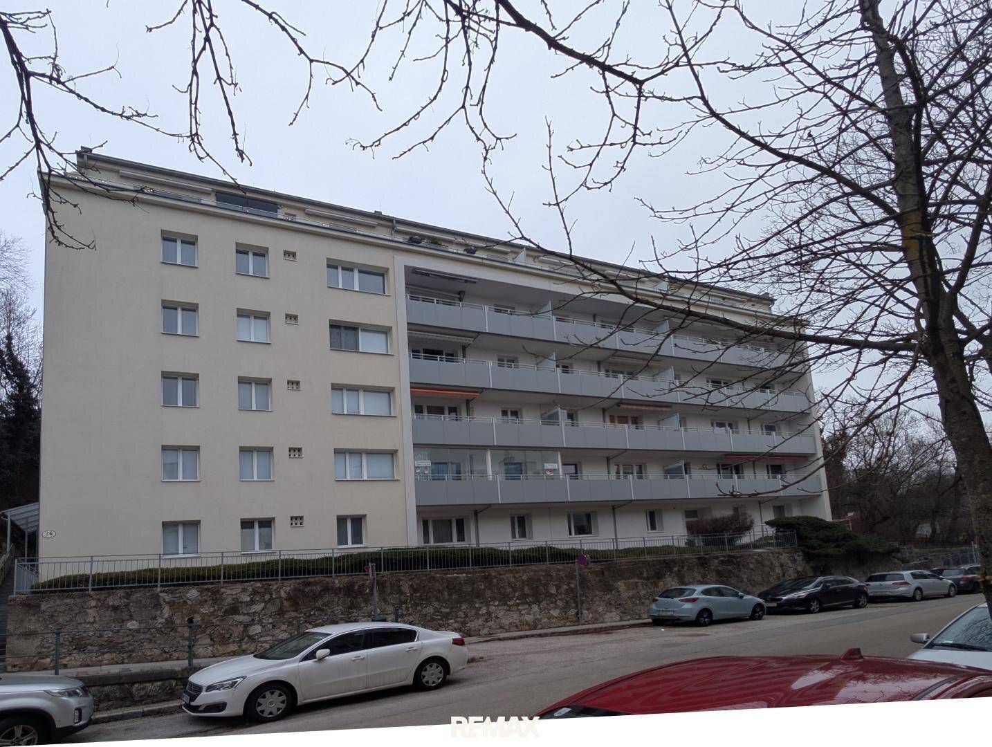 Mehrfamilienhaus mit mehreren Balkonen und einer hellen Fassade in städtischer Umgebung.