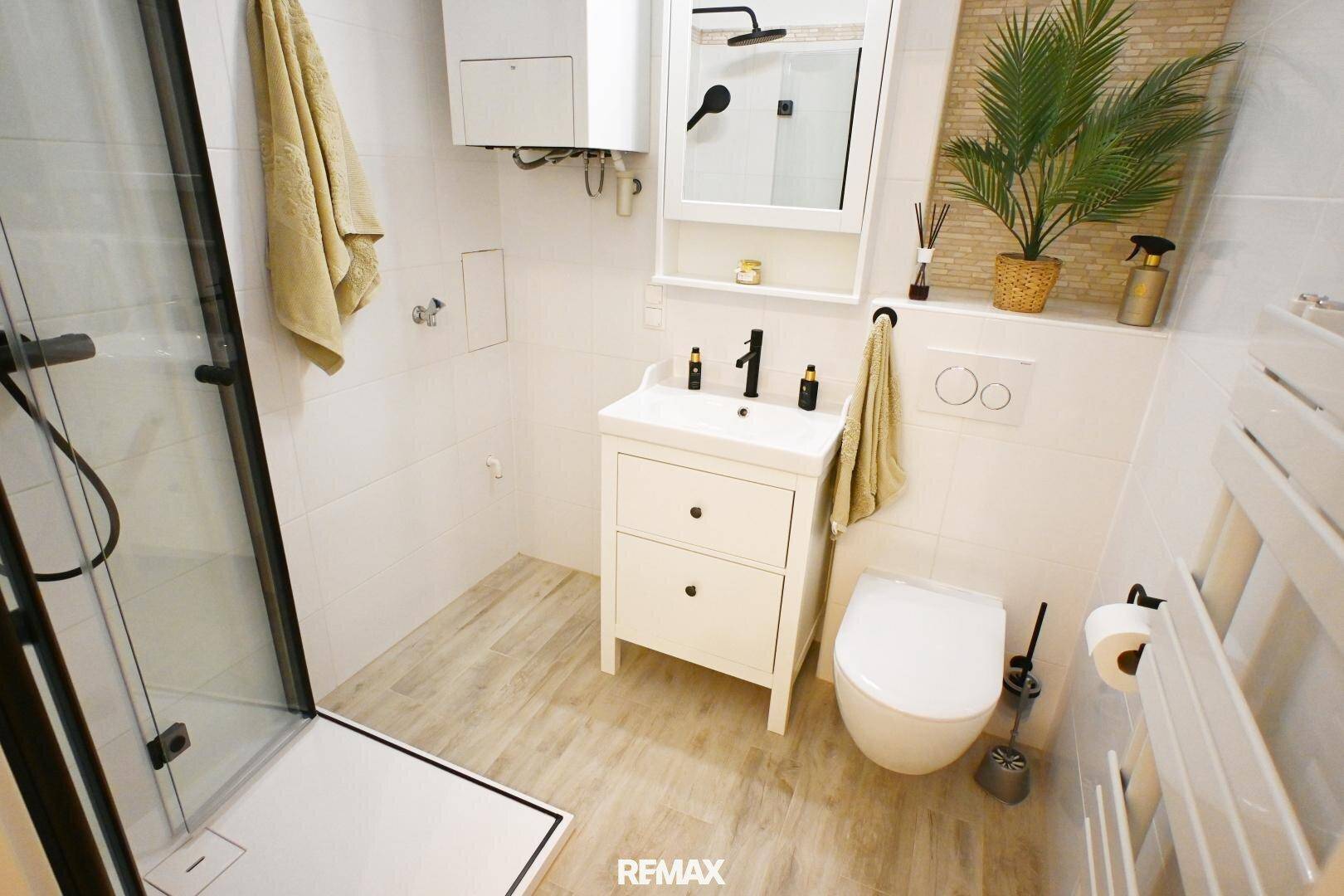 Modernes Badezimmer mit Dusche, WC, Waschbecken und beheiztem Handtuchhalter.