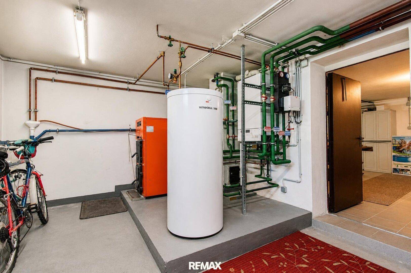 Heizraum im Keller mit moderner Heizungsanlage, Warmwasserspeicher und Fahrrädern.