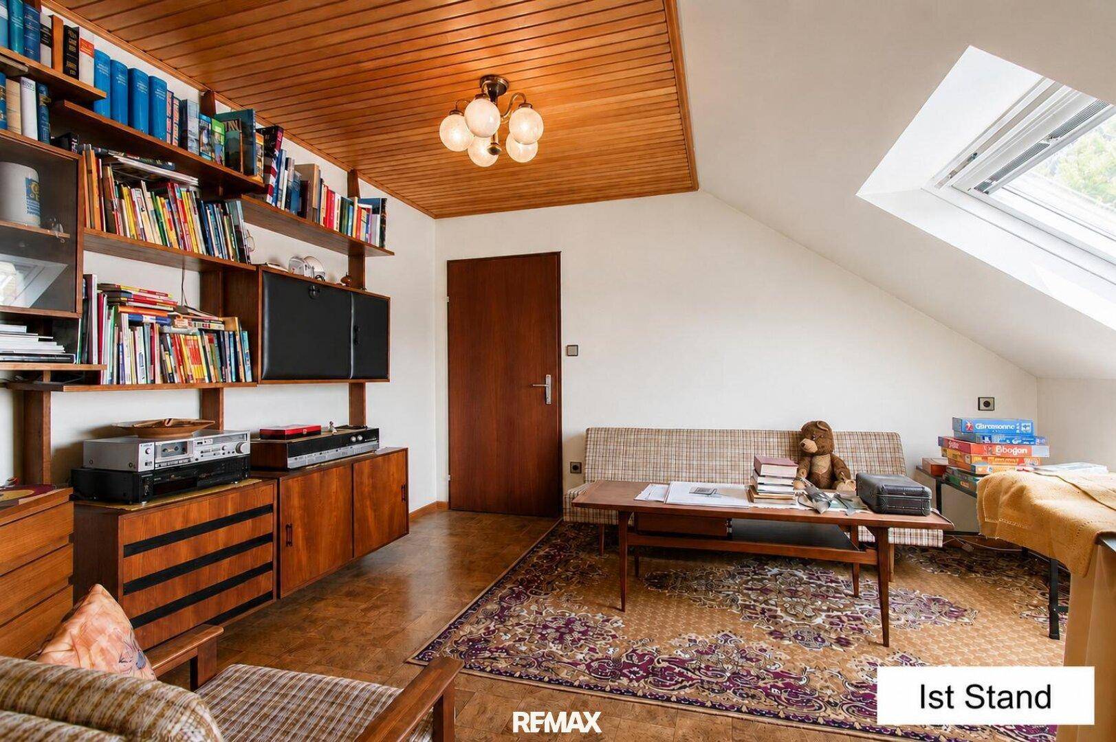 Dachgeschosszimmer mit Bücherregalen, Dachfenster und gemütlicher Sitzecke im Vintage-Stil.