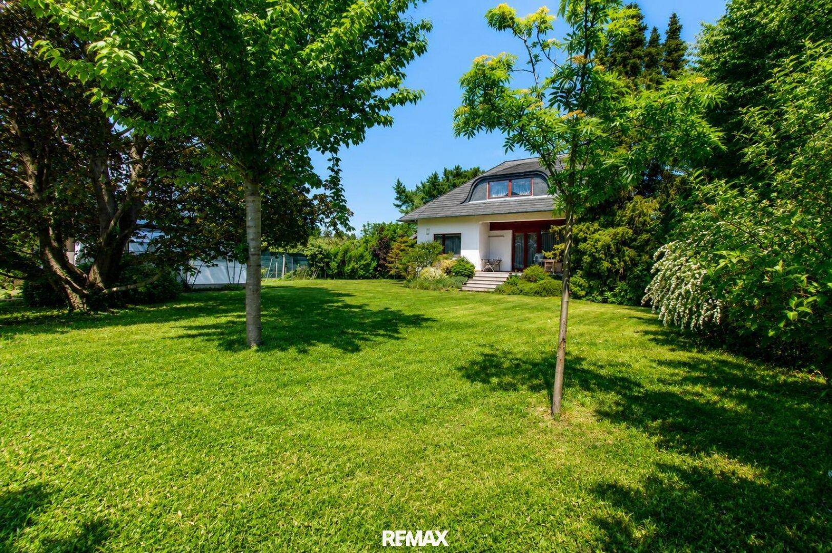 Weitläufiger grüner Garten mit altem Baumbestand und viel Rasenfläche um das Haus.