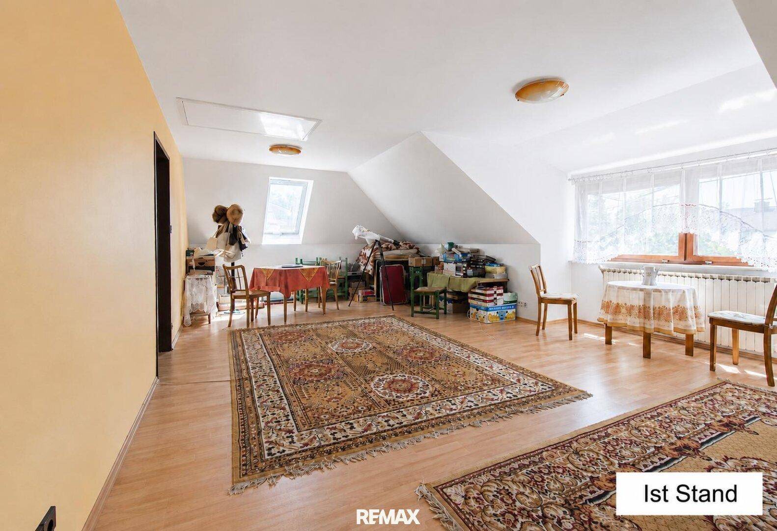Geräumiges Dachgeschosszimmer mit Teppichen, Tischen und viel Tageslicht.