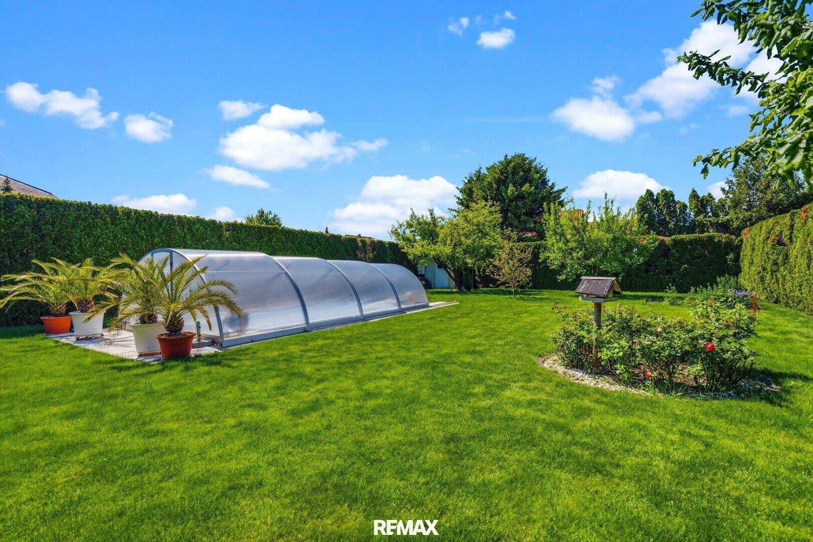 Weitläufiger Garten mit großem überdachtem Pool, weitläufiger Rasenfläche und üppiger Bepflanzung.