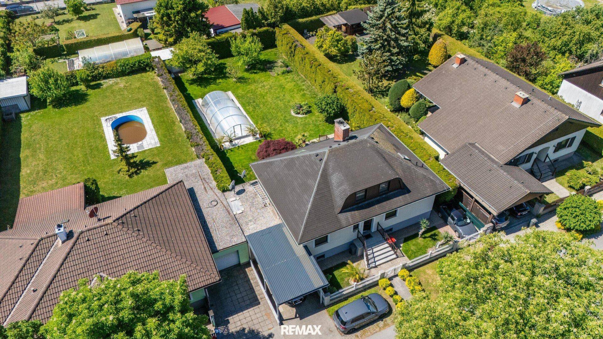 Luftaufnahme des Anwesens mit Einfamilienhaus, großem Garten, Pool und umliegender Wohngegend.