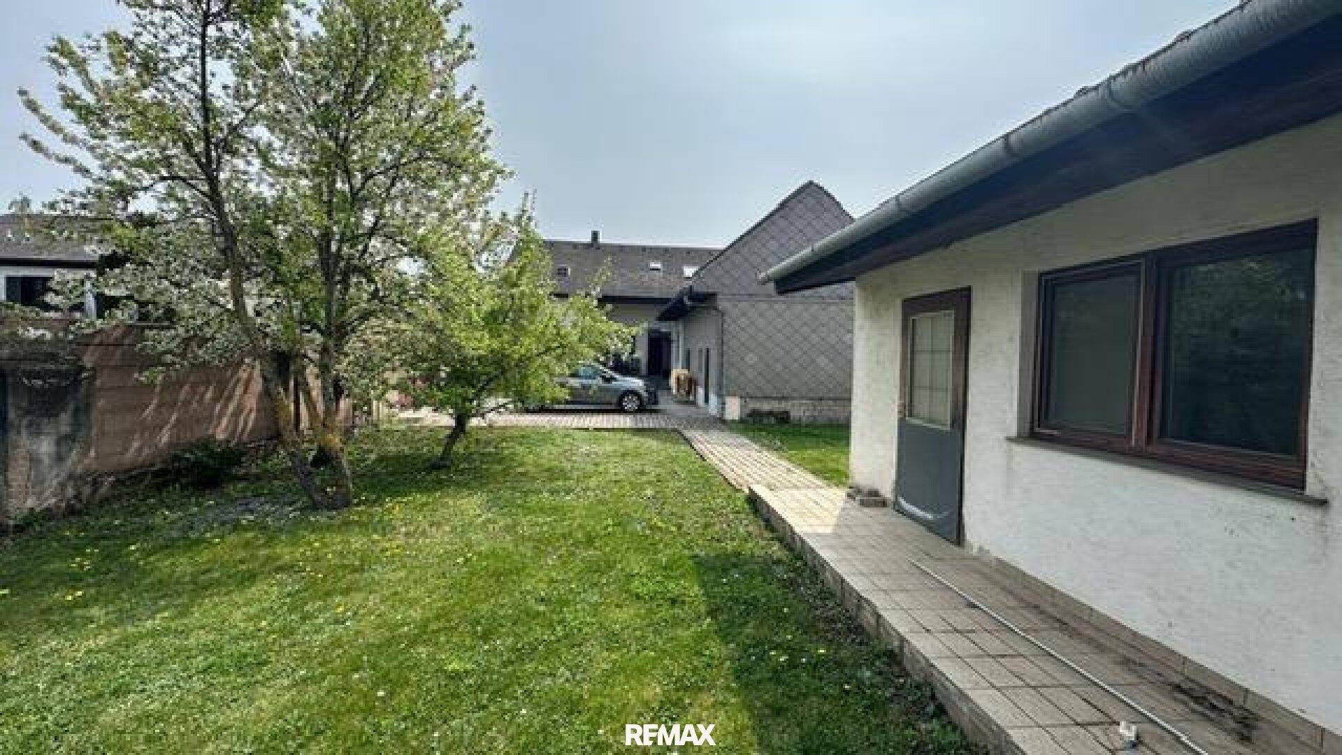 Grüner Gartenbereich mit Rasenfläche und Bäumen neben dem Haus.