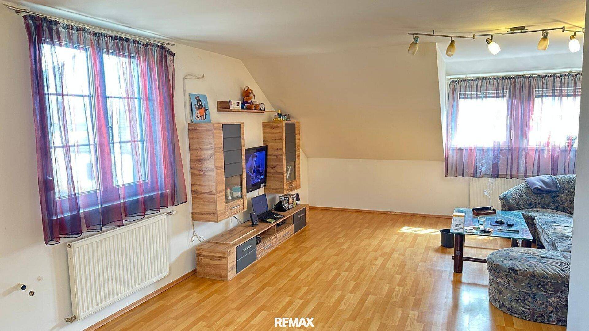 Helles Wohnzimmer im Dachgeschoss mit Holzboden und schrägen Wänden.