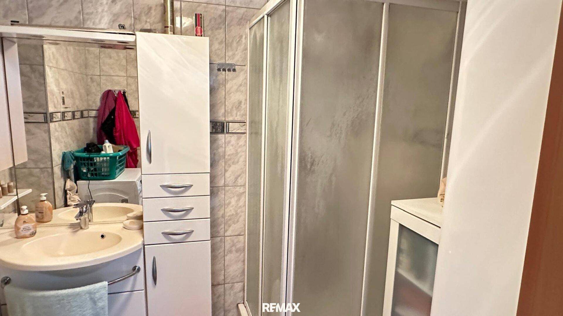 Badezimmer mit Duschkabine, Waschbecken und Spiegelschrank.
