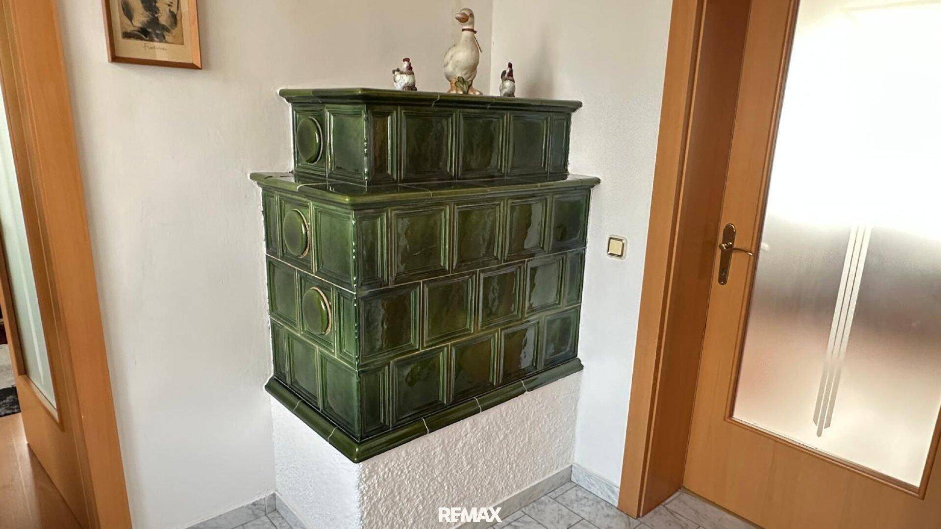 Grüner Kachelofen im Flur, der Wärme und traditionellen Charme verleiht.