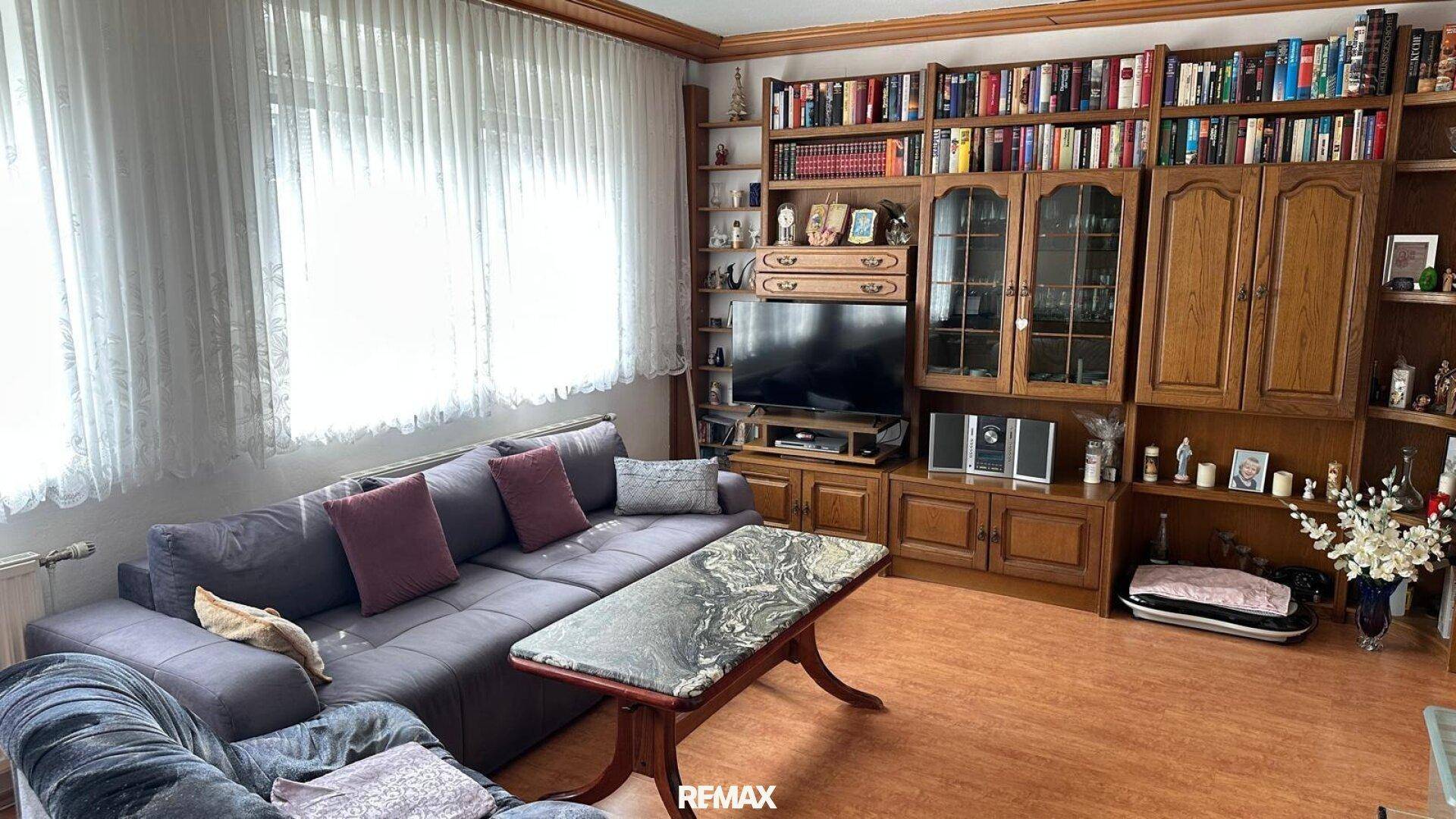 Geräumiges Wohnzimmer mit großem Sofa, Bücherregal und Holzboden.