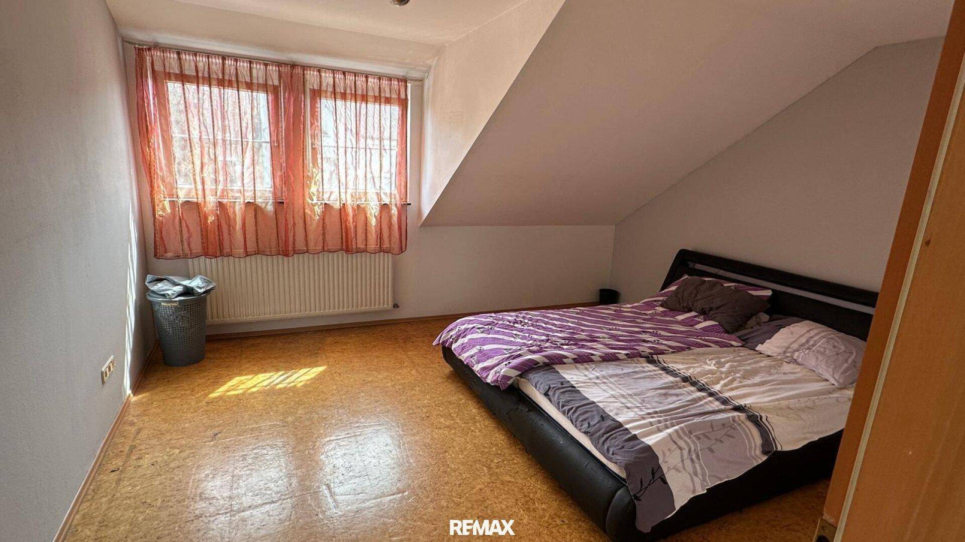 Schlafzimmer im Dachgeschoss mit schrägen Wänden und Doppelbett.